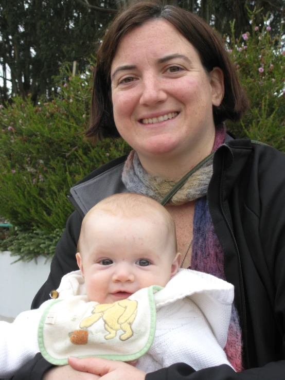 a woman holding a baby who has a bib around his neck