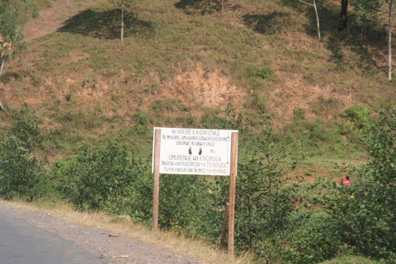 the signs are on a roadside with grass and brush