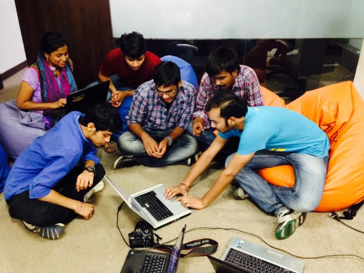 several people sitting in an office, one using a laptop