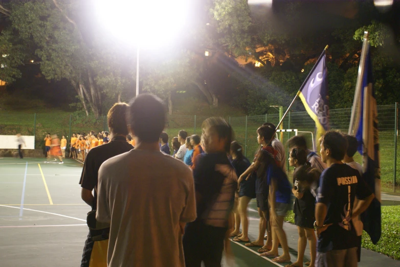 a group of people on a tennis court next to a light