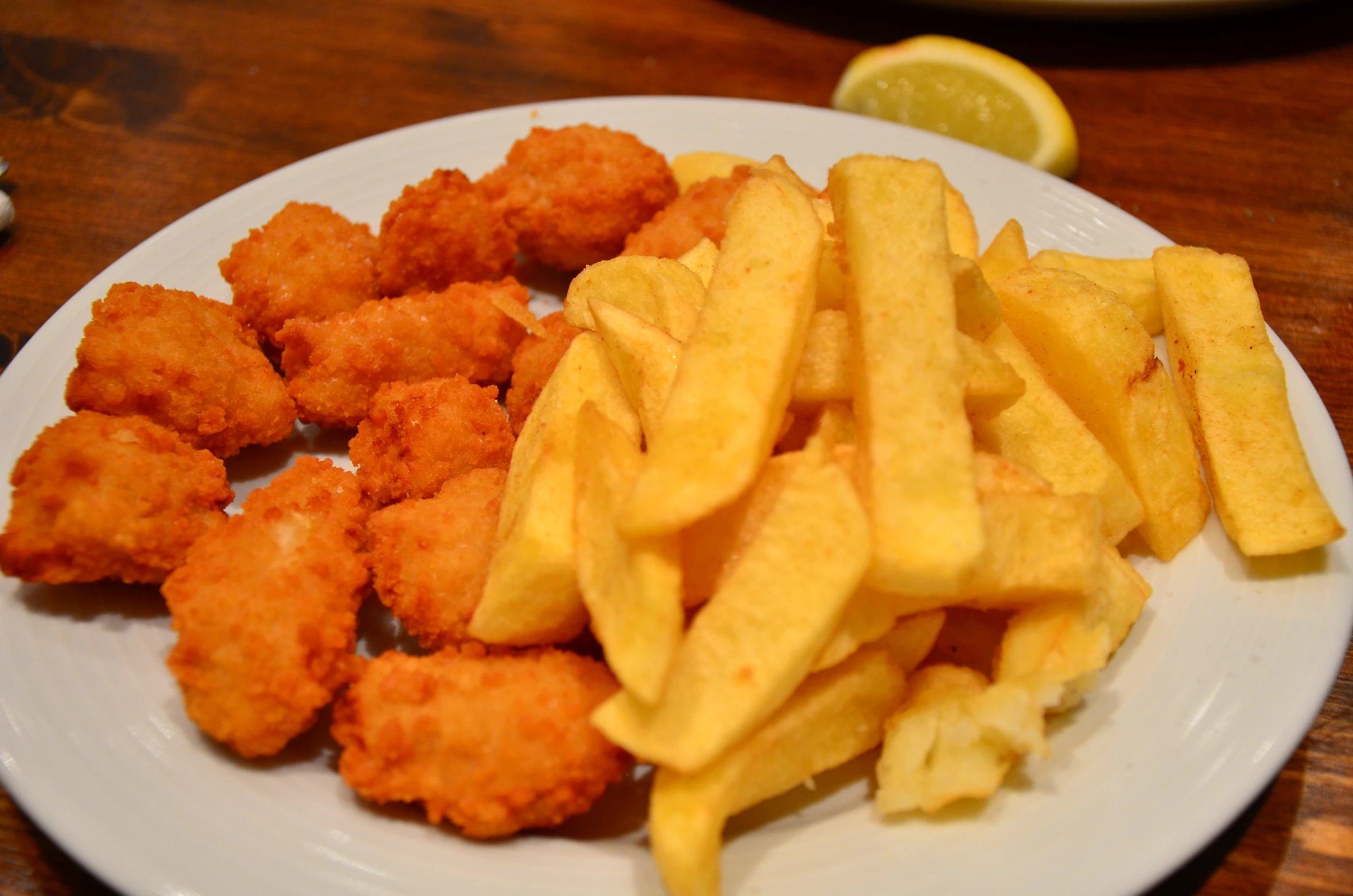 a plate of chicken nuggets and fries, with an orange wedge