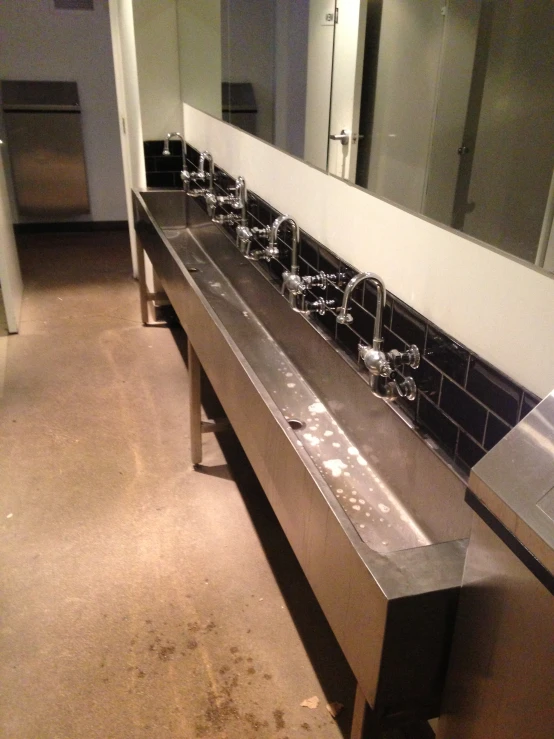 bathroom sinks and mirrors are lined up on a tiled wall