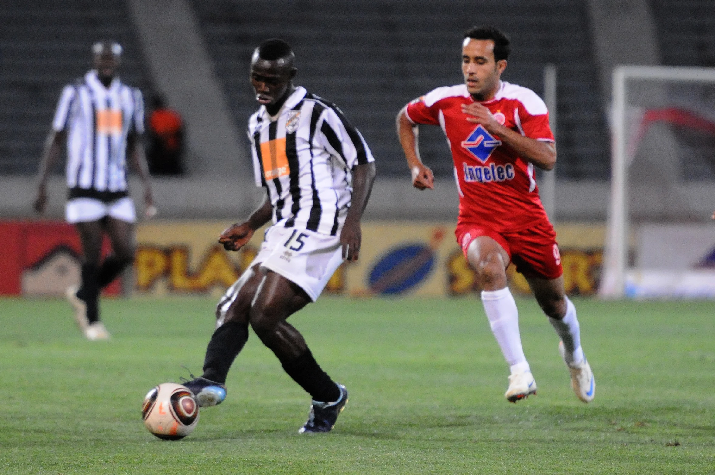 a couple of young men kicking a soccer ball around a field