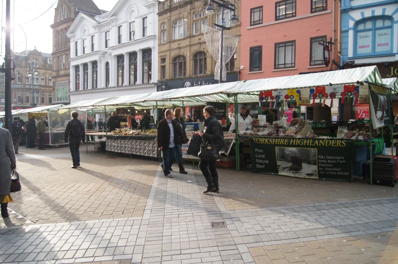 people shopping on a busy street next to shops