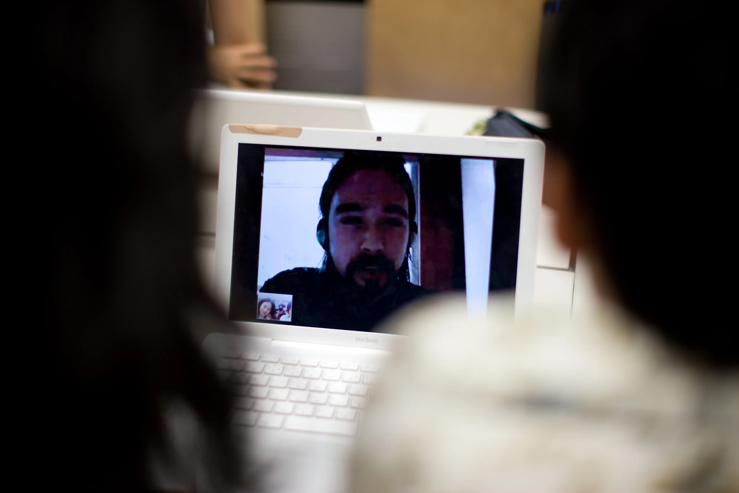 a man in a laptop face is seen in the reflection