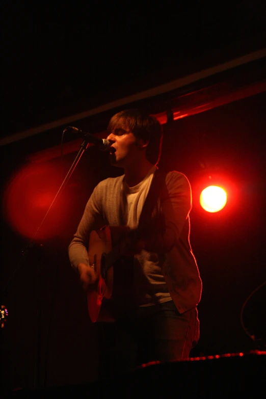a man standing at a microphone with red lights