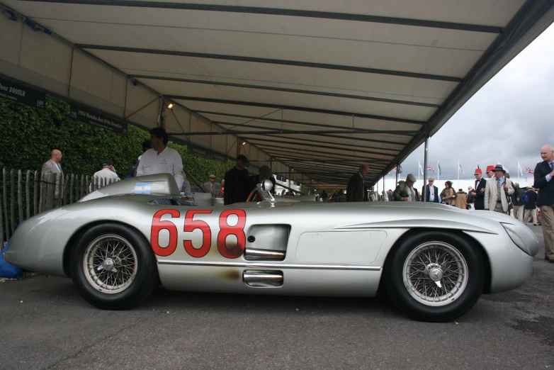 an old style sports car sitting under a canopy