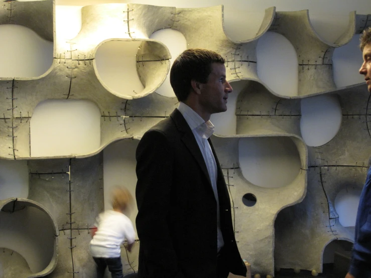 two men are talking in front of several suspended light fixtures