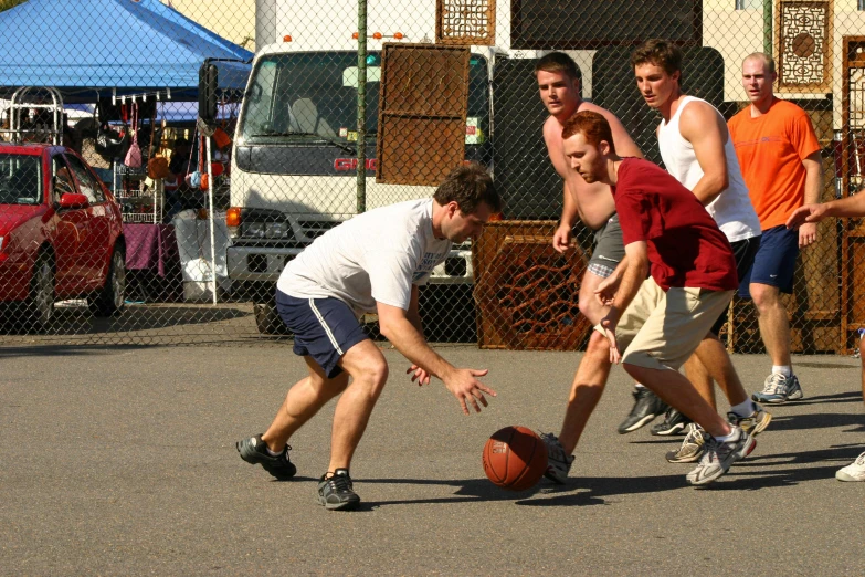 a man trying to block another man in the street with a ball