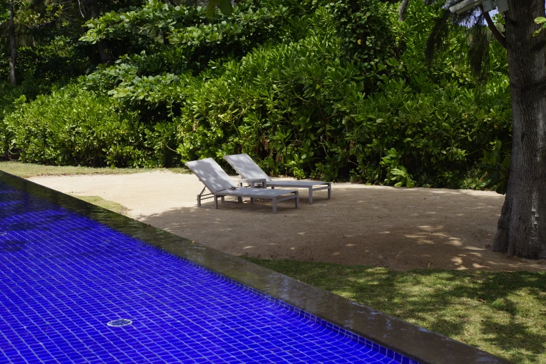 two lounge chairs sitting next to a pool