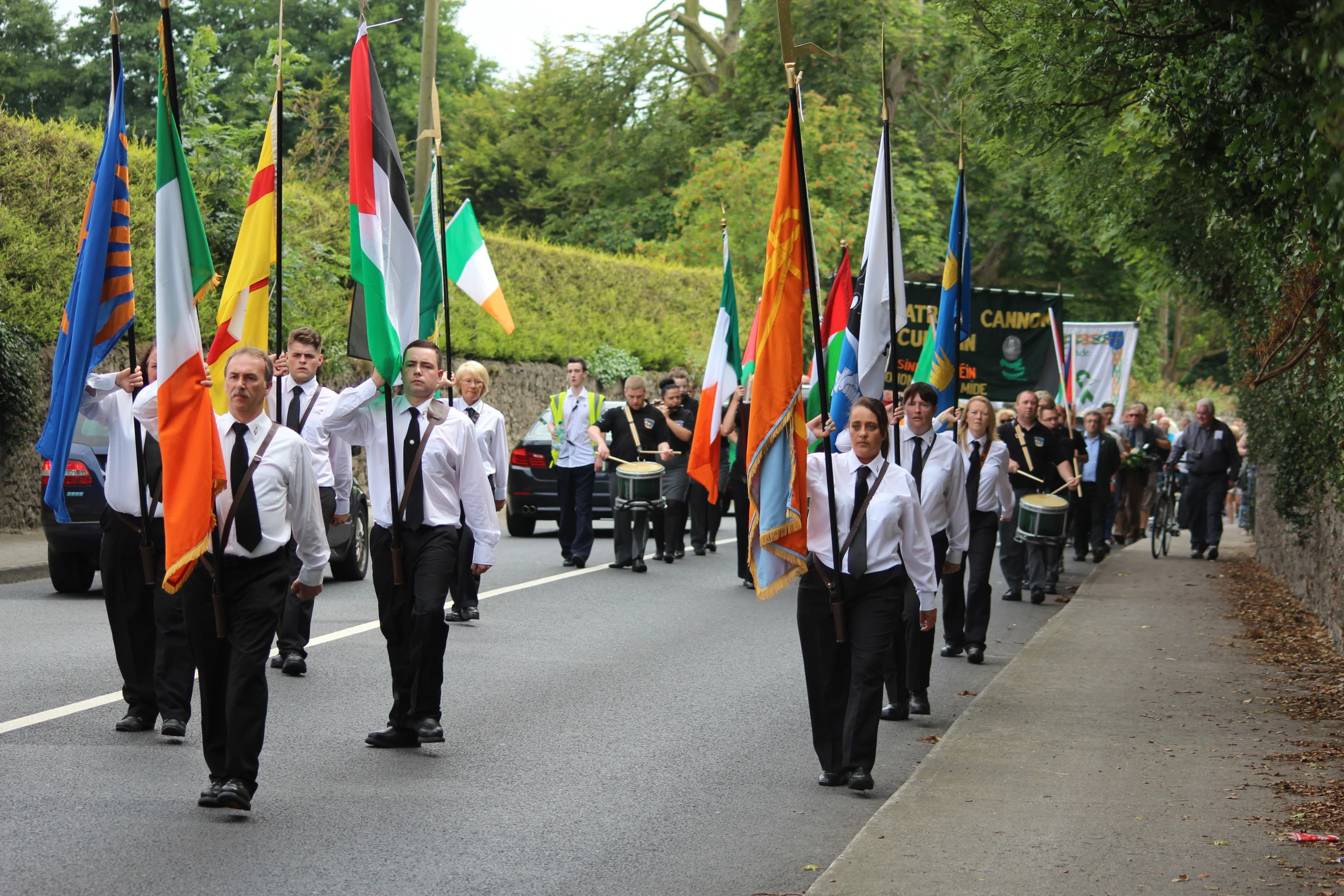 men are carrying flags down the street in formation