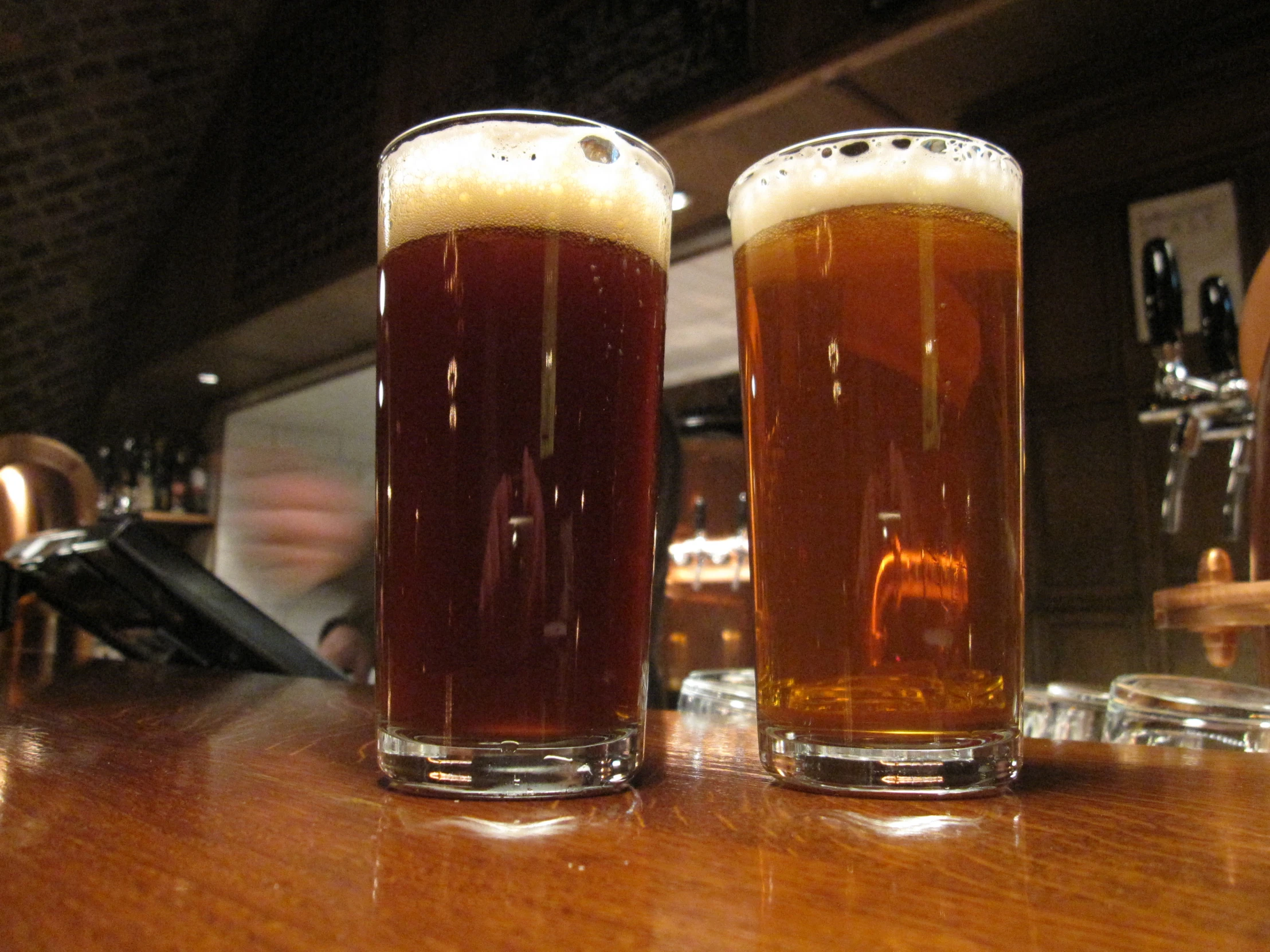 two glasses of beer sit on the bar