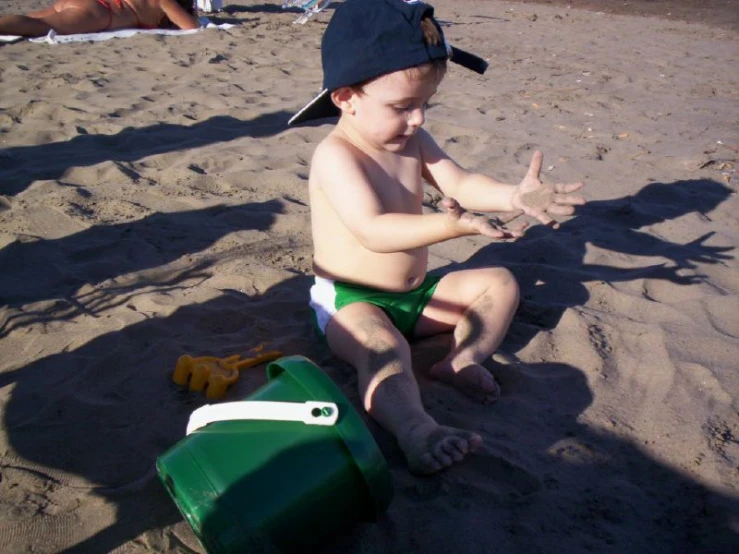 a small child sitting in the sand at the beach