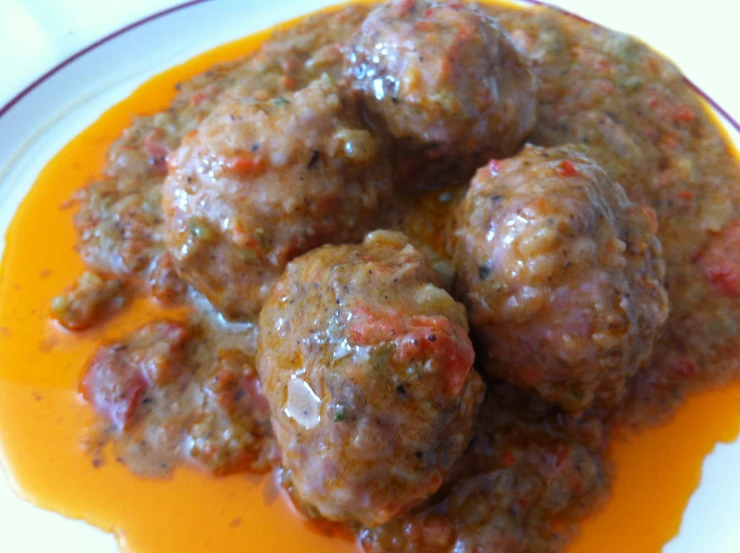 meatballs are arranged in a round tomato sauce on top of a white plate