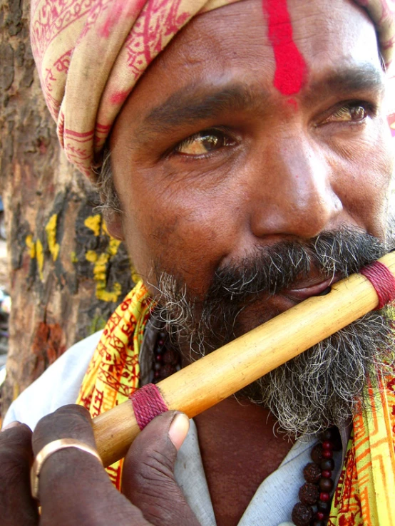 a man in a turban is holding a small wooden pipe
