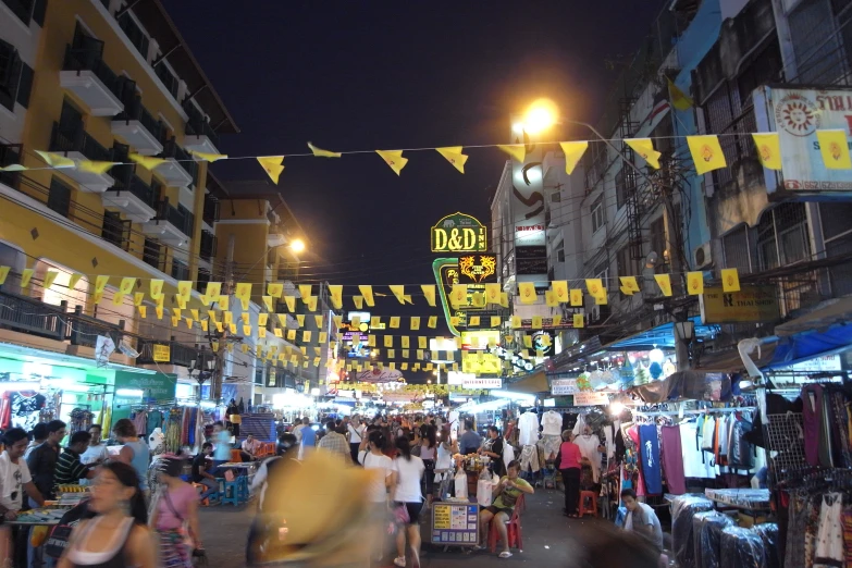 a crowded street at night with several people shopping