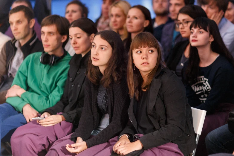 a group of people sitting down and some looking in the same direction