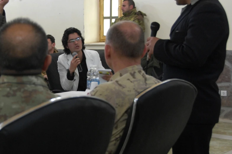 two military officers are being interviewed by a woman in camouflage