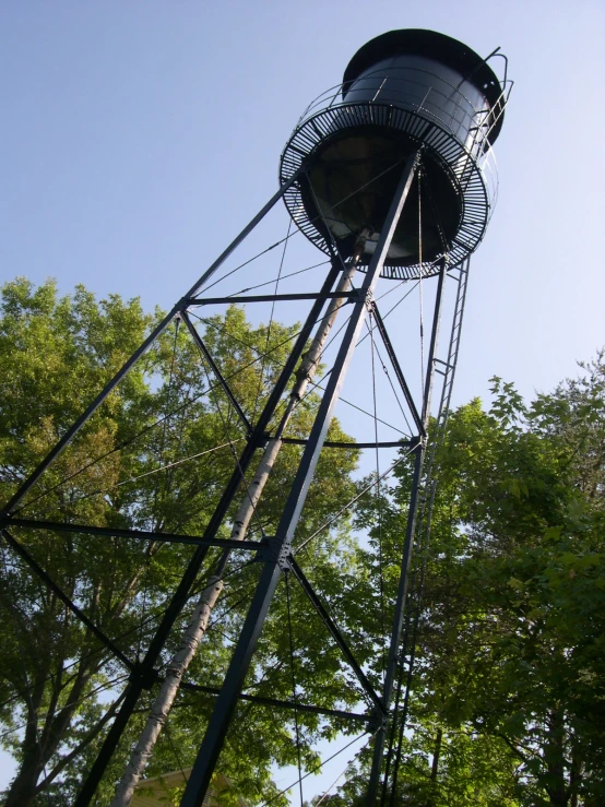 a tall black water tower sitting among the trees