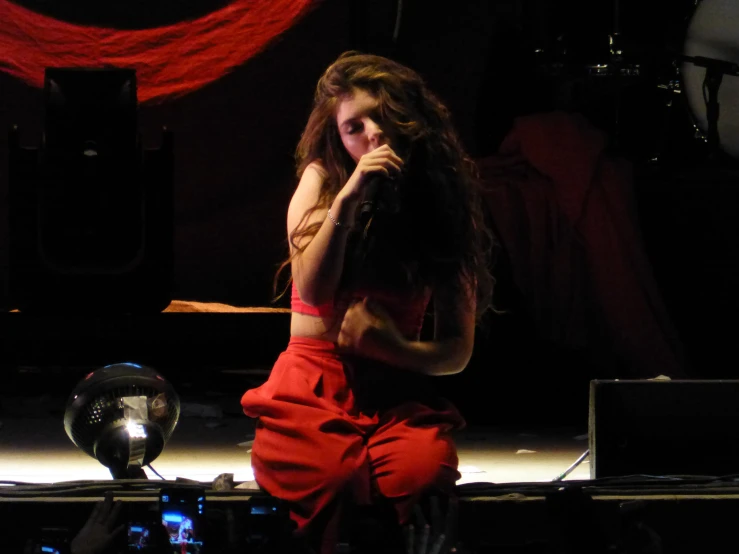 a woman is sitting on a chair, in red pants and a short top