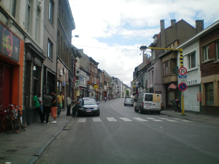 a city street with many cars parked on the side walk and some people walking