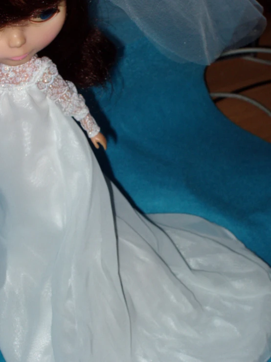 a barbie doll in white dress on a blue blanket