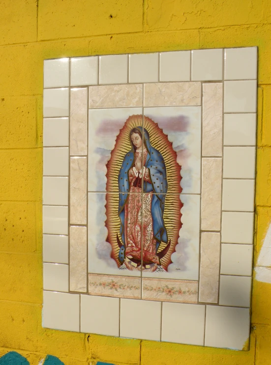 a tile wall with a painting and the likeness of an virgin