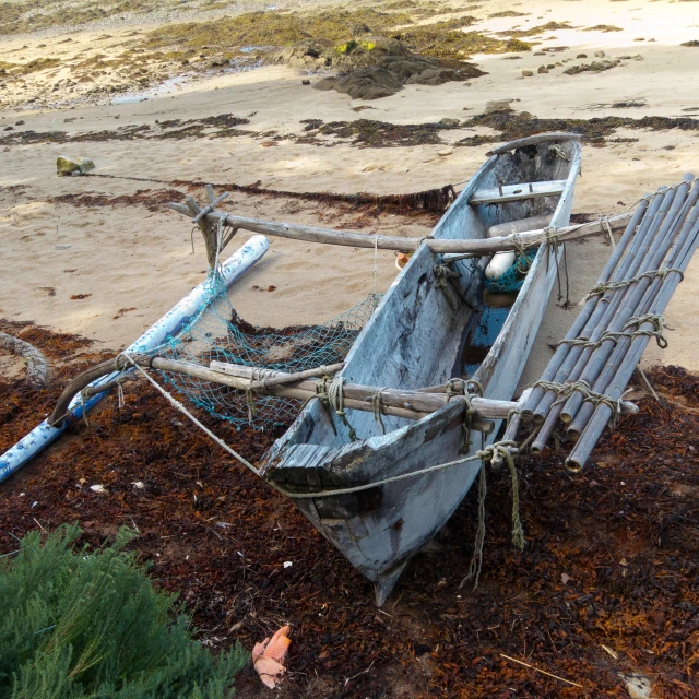 a rowboat sitting in the sand with it's hull up