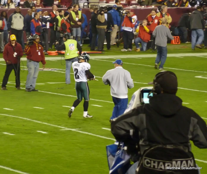 a football player standing on top of a field next to a crowd