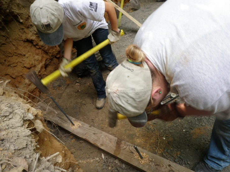 a man is holding a large pair of tools while another holds a shovel