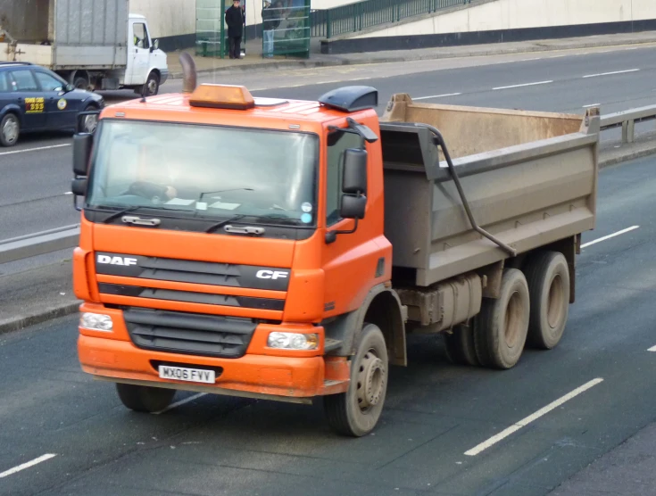 an orange dump truck is on the road