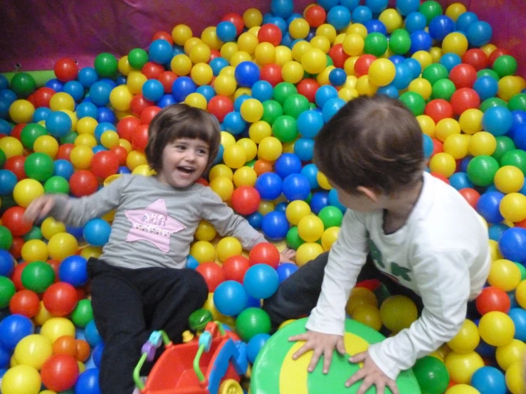 two young children playing in an artificial ball pit