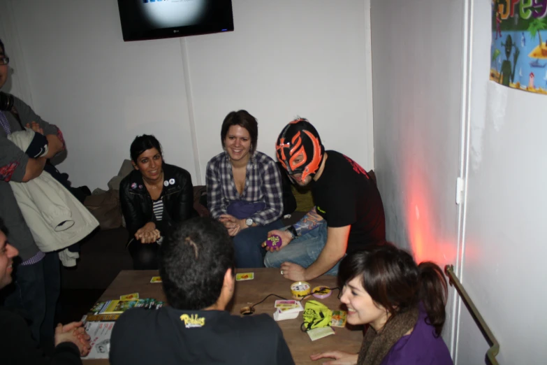 several people sitting around playing cards and smiling