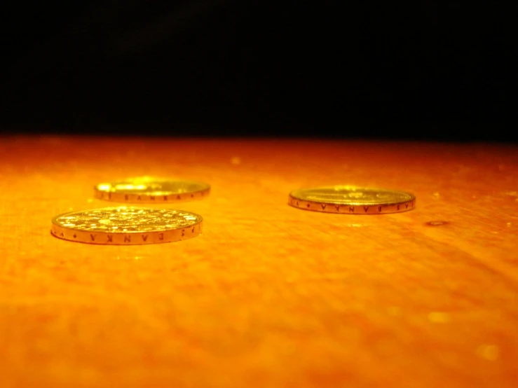 three golden coins sitting on top of a wooden table