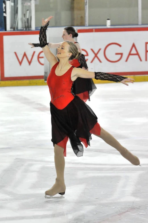 a woman in red and black performing on ice