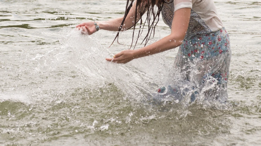 a person standing in a body of water with their arm out and one hand stretched out