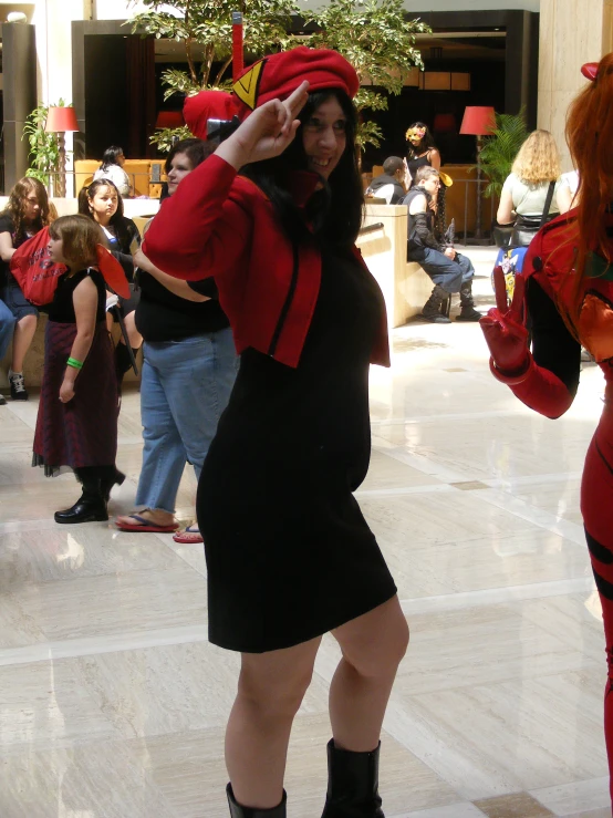 a woman in black dress and hat standing by others