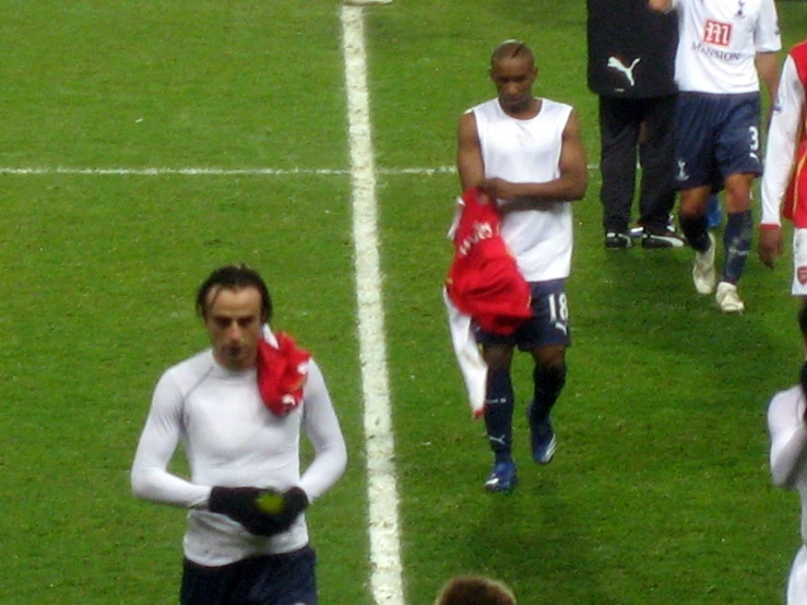 two soccer players are walking with some people on a field