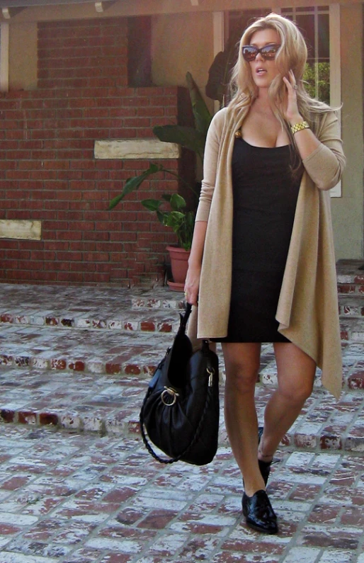 a woman walking down a brick pathway carrying a black bag