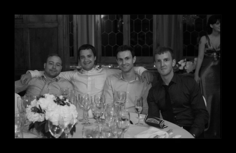 four men sitting at a table with wine glasses