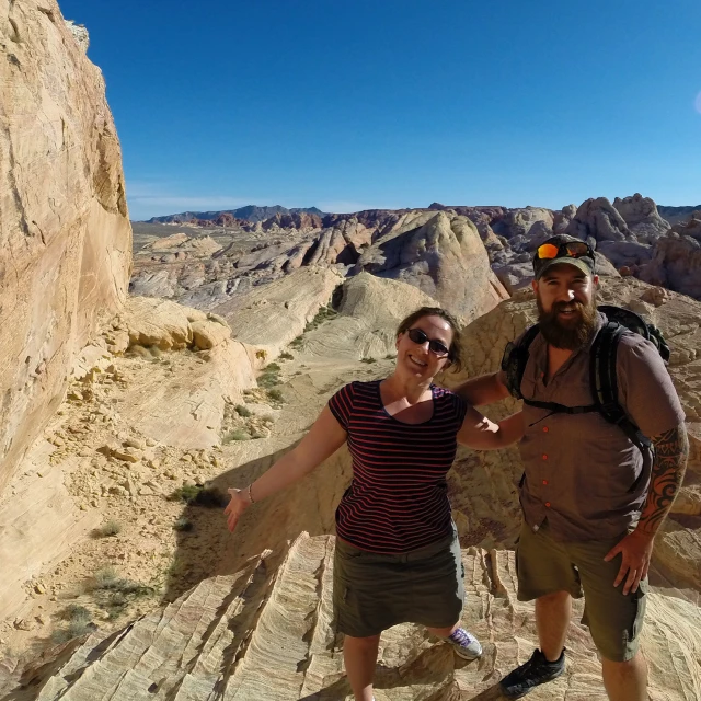 two people posing on a rocky area with mountains in the background