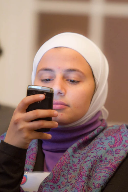 woman in head scarf using cell phone in living room