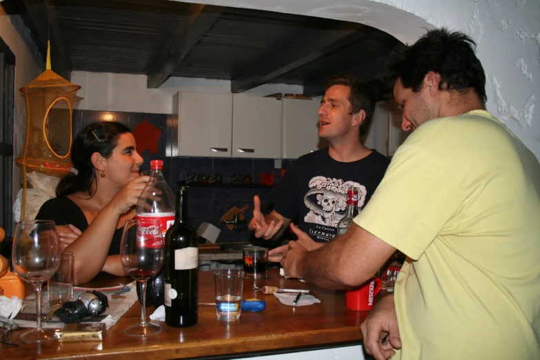 two men and two woman talking to one another at a table with glasses of wine