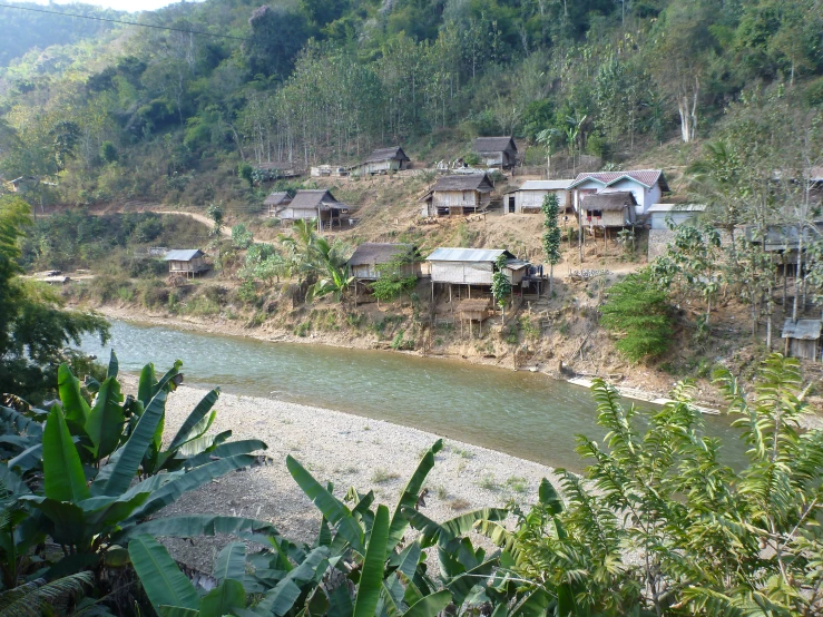 a green river in the foreground and a village on the opposite bank