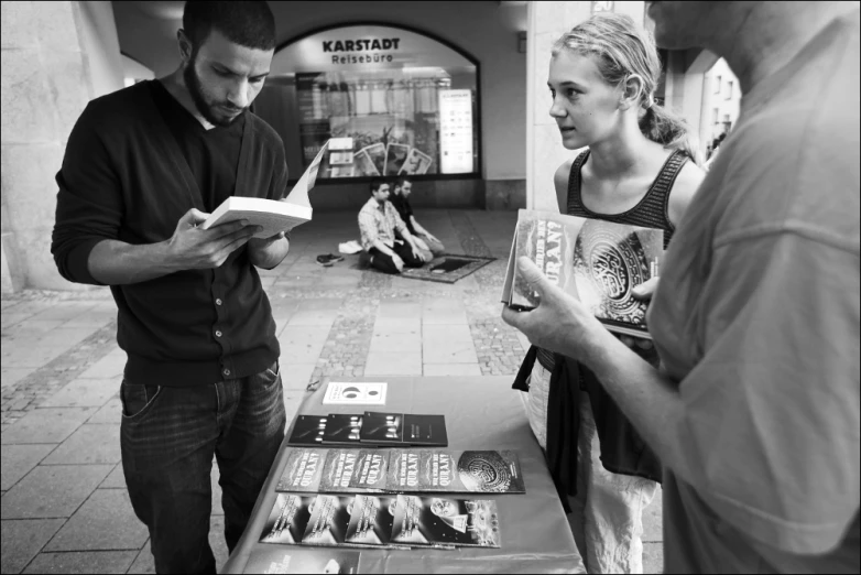 two people reading books in a bookstore while one looks at them