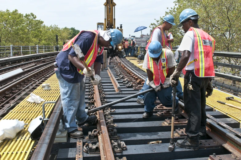 there is three construction workers that are on the track