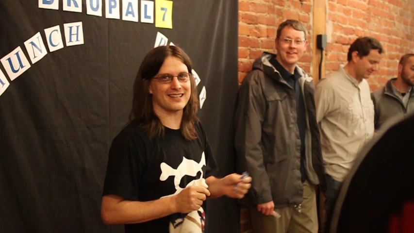 there are three people smiling next to a brick wall