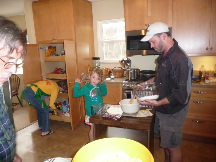 man and children standing in kitchen next to large bowl