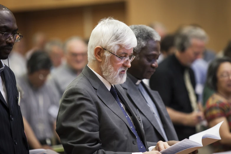 a man with glasses sitting down at a conference table