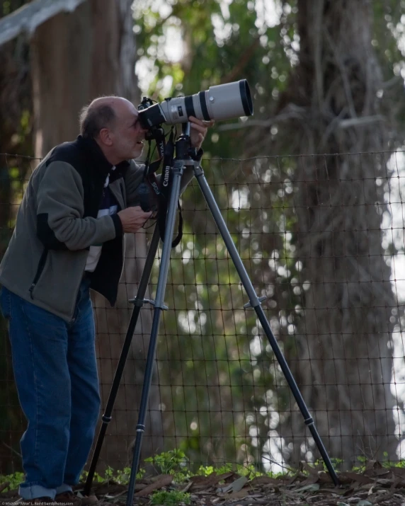 a man standing next to a fence with a camera